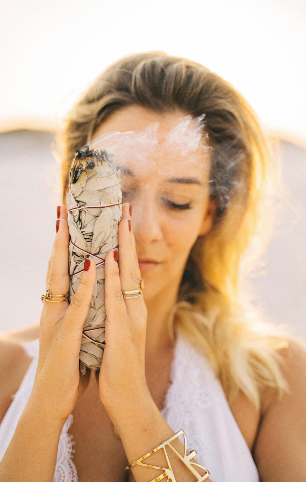 Lady meditating with a smoking smudge stick near her face