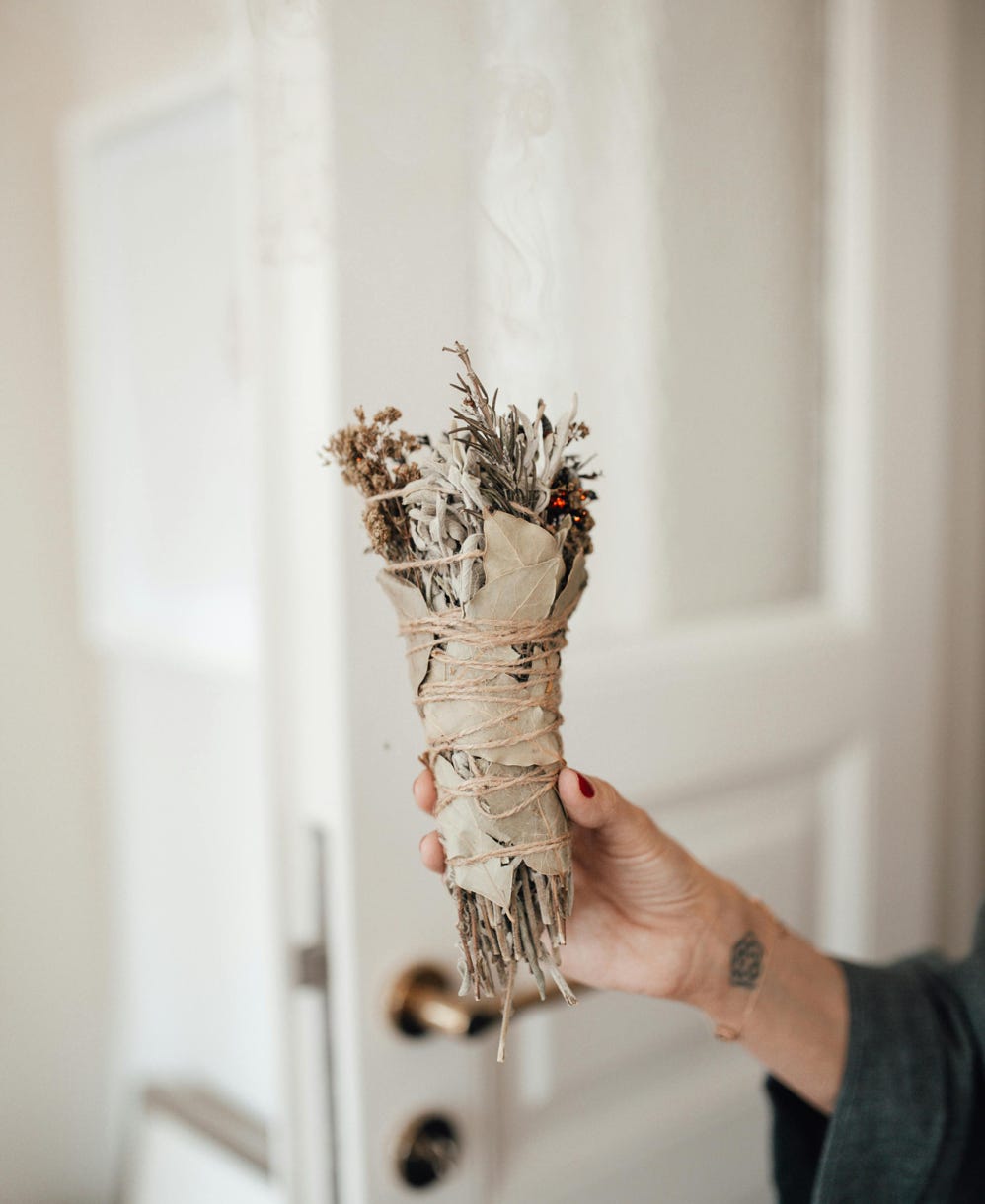 Bountiful smudge bundle slightly smoking in the hands of a lady, clearing space